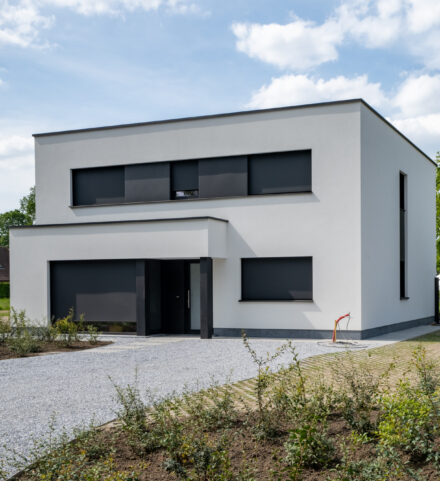 Moderne nieuwbouwwoning met strakke lijnen, witte gevel en grote raampartijen