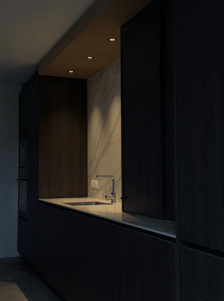 Luxe keukenafwerking in een nieuwbouw woning met donkere kasten, ingebouwde verlichting en marmeren achterwand als voorbeeld van maatwerk