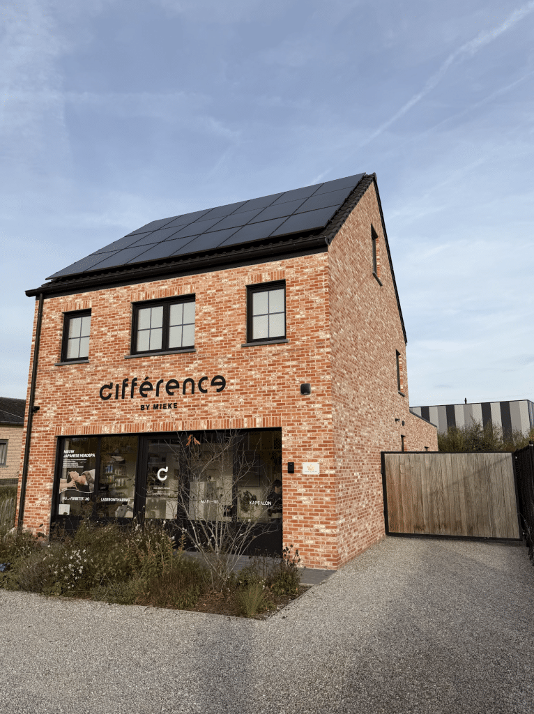 Modern nieuwbouw handelspand van rode baksteen met zonnepanelen op het dak en een grote glazen pui, waarin een onderneming is gevestigd