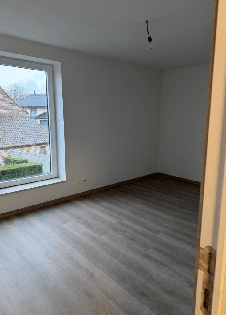 Moderne slaapkamer met warme parket vloer in houtlook en veel natuurlijk licht
