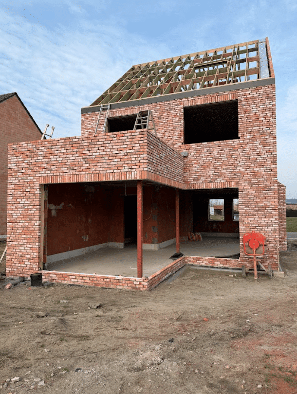 Ruwbouw woning in opbouwfase met zichtbare structuur en dakconstructie.
