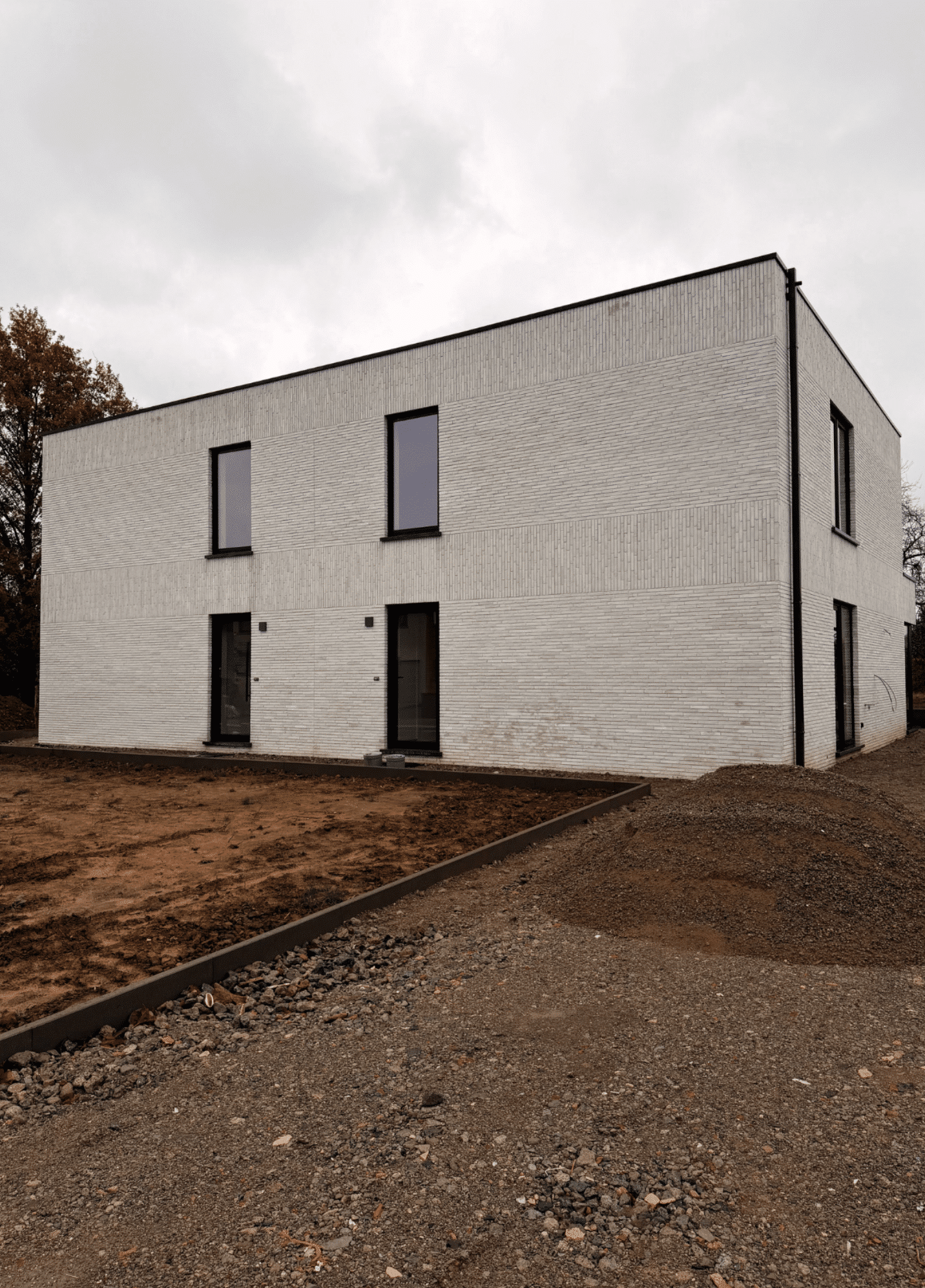 Strakke nieuwbouwwoning in casco fase met afgewerkte gevel en buitenschrijnwerk.
