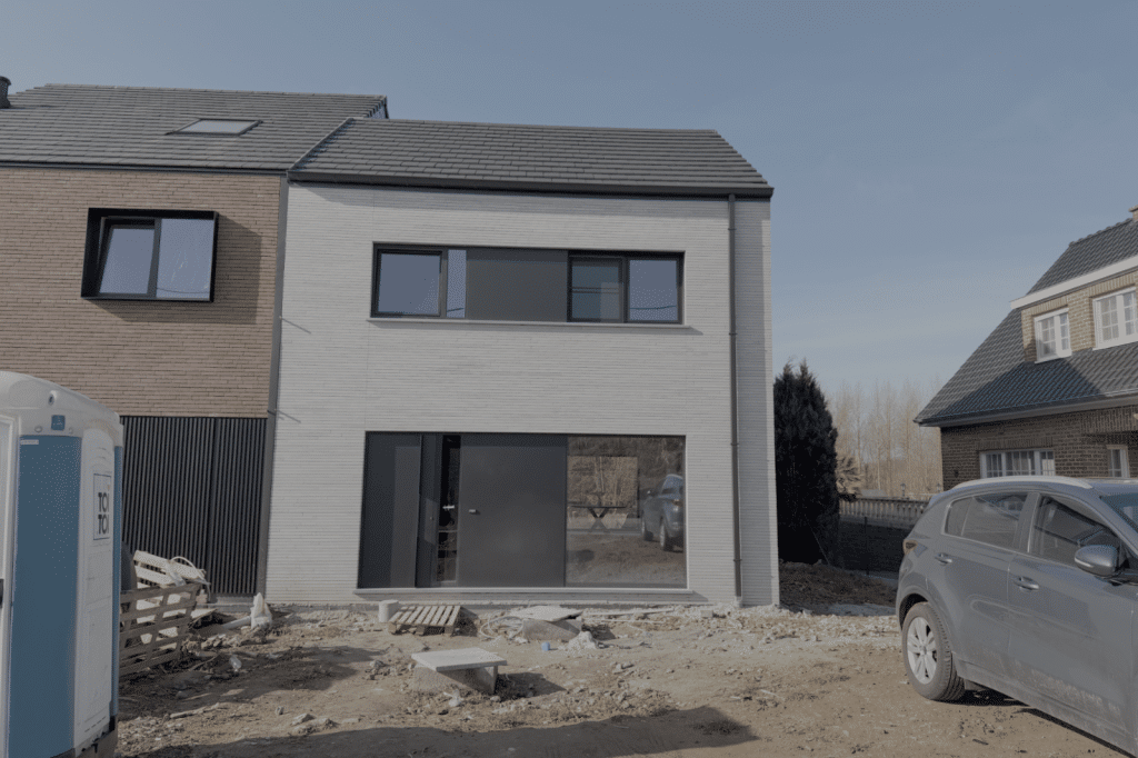 Compacte nieuwbouwwoning met strakke gevelsteen en grote raampartijen in de eindfase van de bouw.