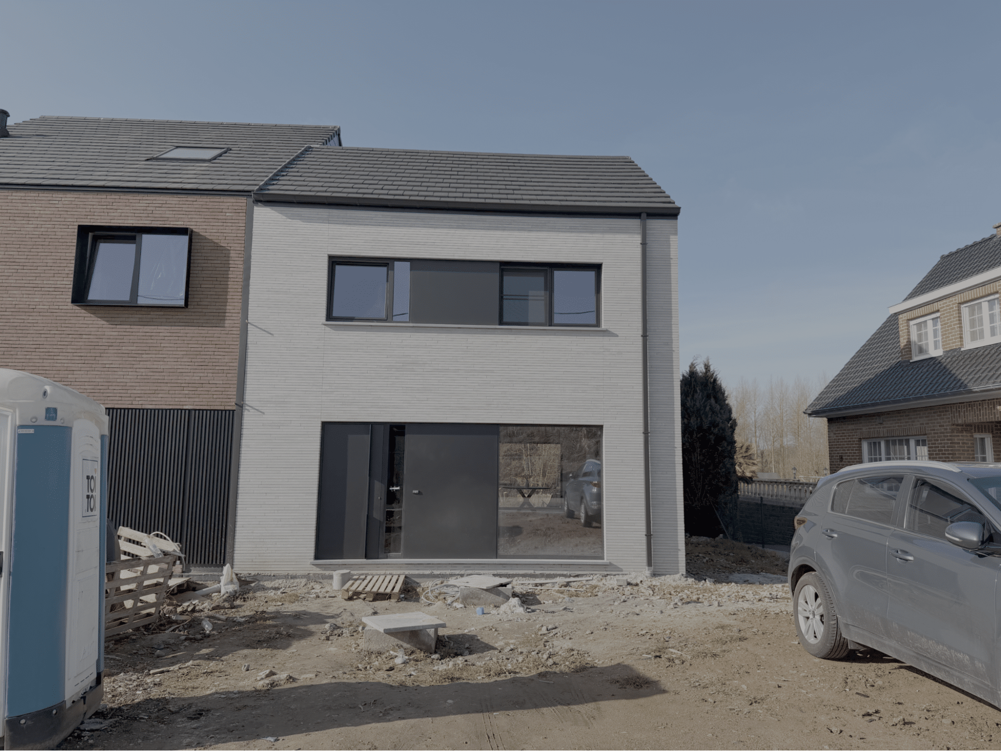 Compacte nieuwbouwwoning met strakke gevelsteen en grote raampartijen in de eindfase van de bouw.