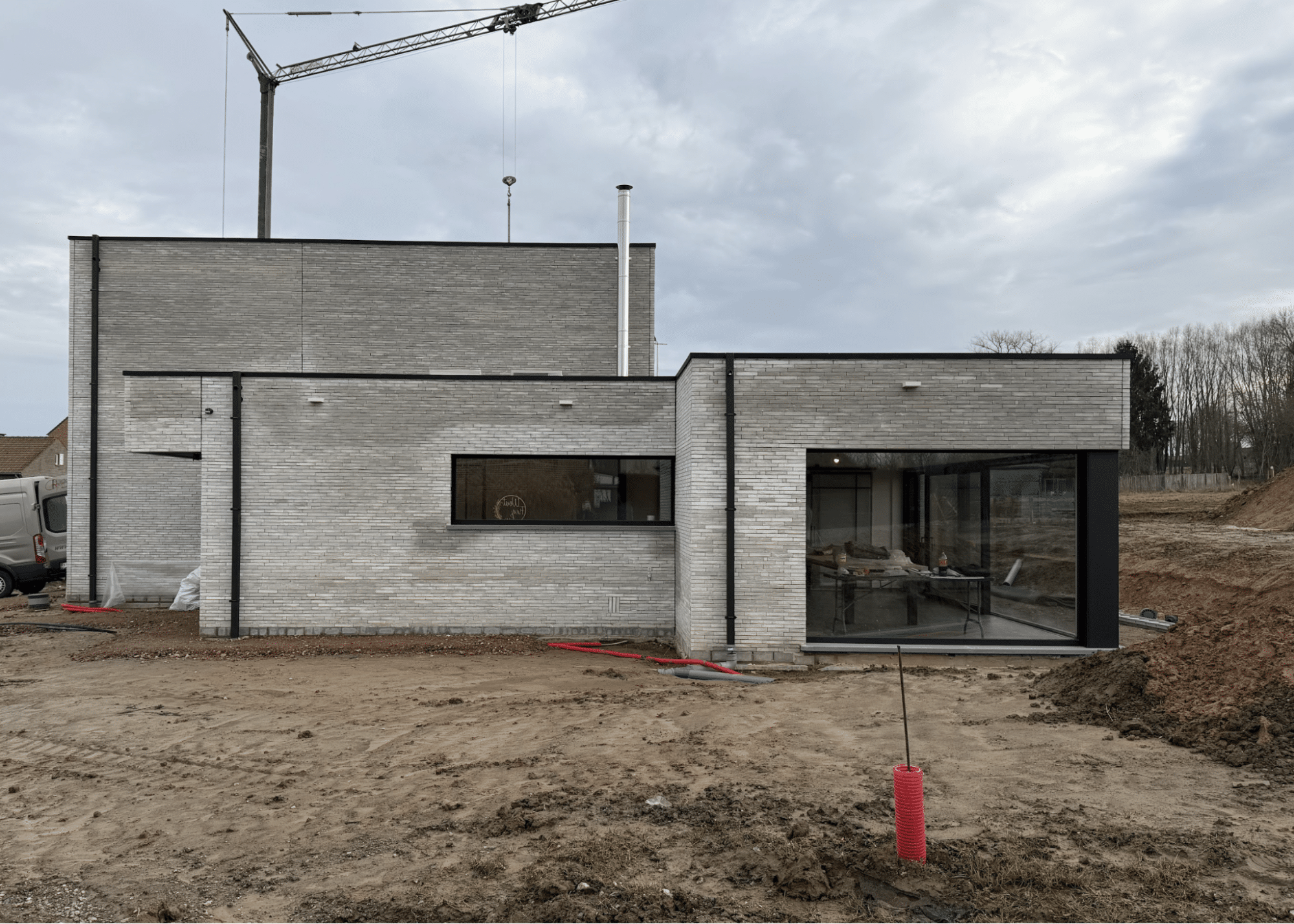 Moderne nieuwbouwwoning in opbouw met lichte gevelsteen en grote raampartijen.