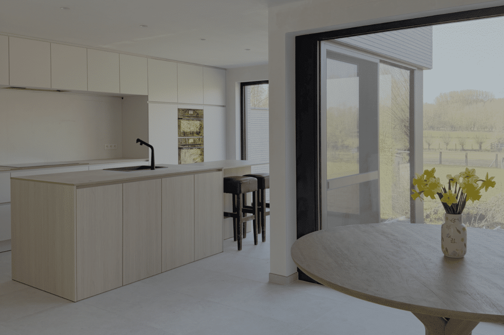 Lichte, strak afgewerkte keuken in een nieuwbouwwoning met zicht op de tuin.