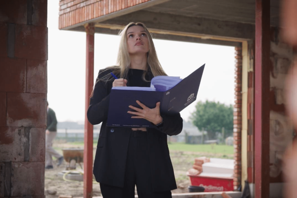 Een bouwcoördinator van NB-Projects inspecteert de werf en noteert observaties in haar bouwdossier.