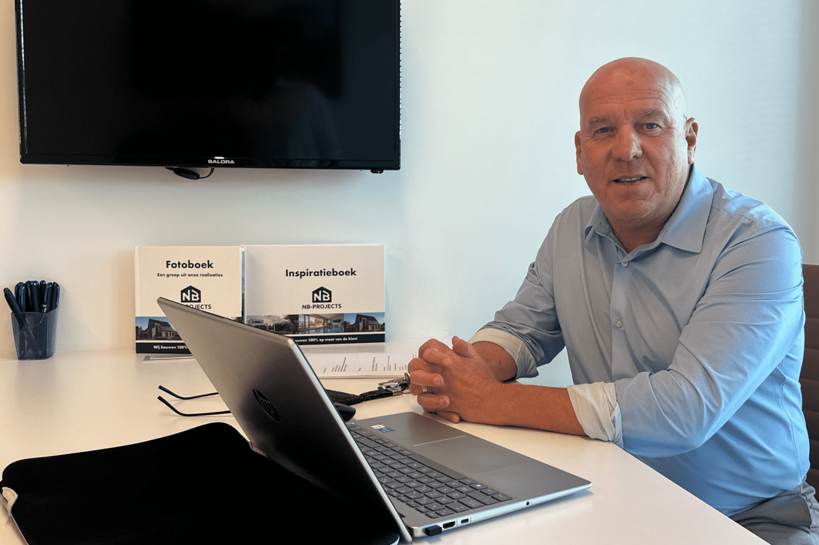 Adviseur van NB-Projects aan het bureau met het foto- en inspiratieboek binnen handbereik
