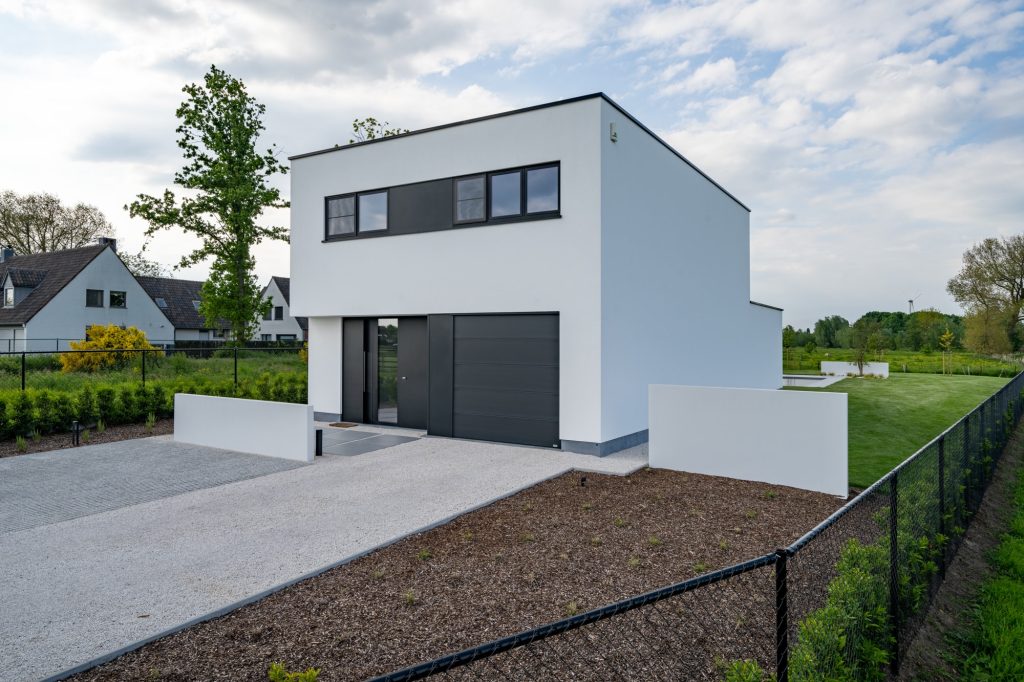 Afgewerkte moderne nieuwbouwwoning met witte gevel, garage en aangelegde oprit
