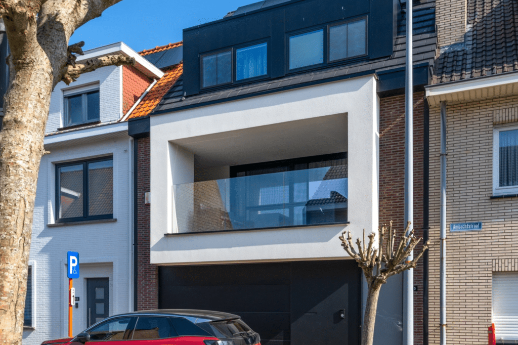 Gesloten bebouwing met moderne witte gevel, zwart buitenschrijnwerk en glazen balkon