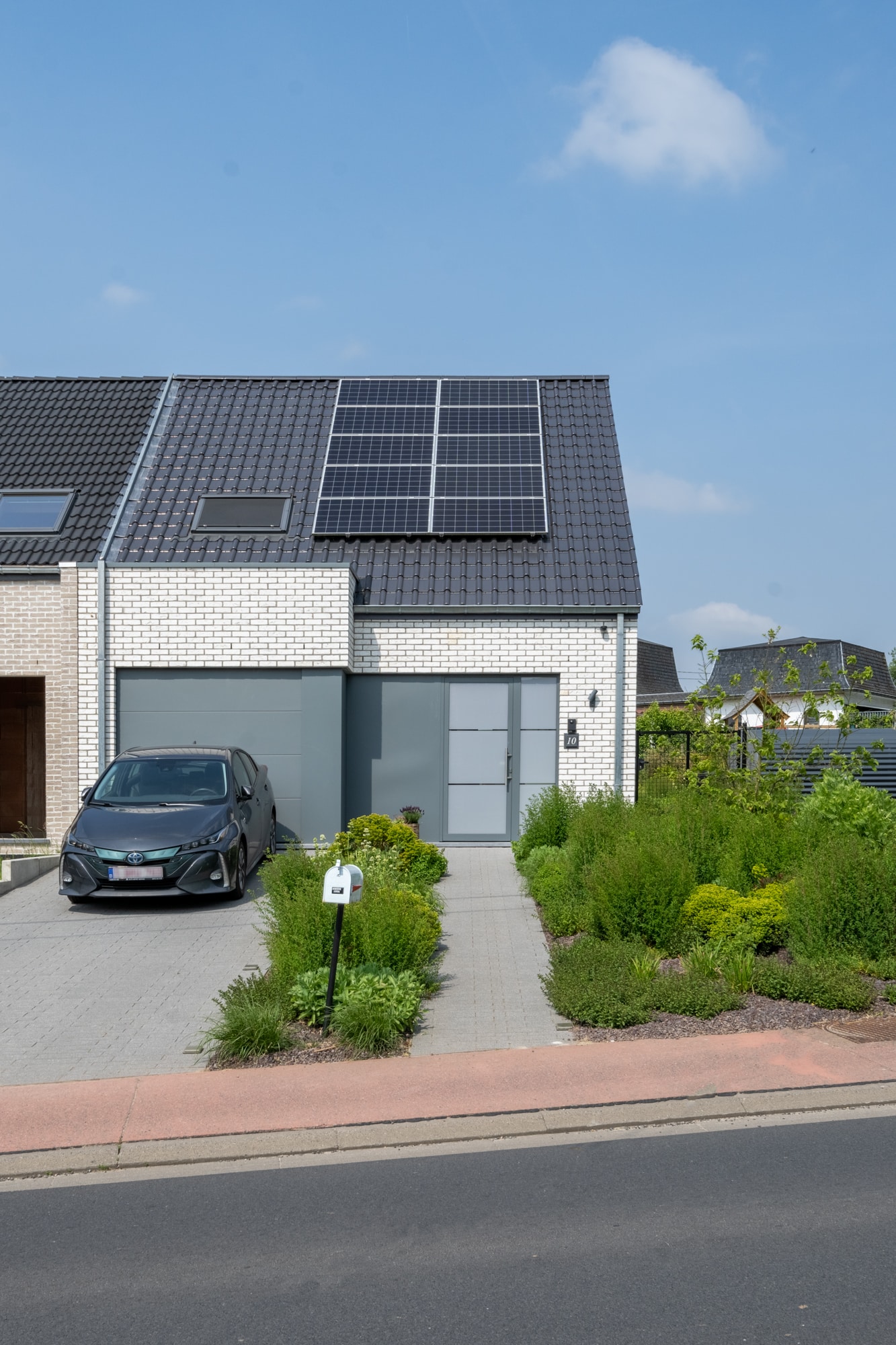 Halfopen bebouwing met zonnepanelen, oprit, garage en groene voortuin