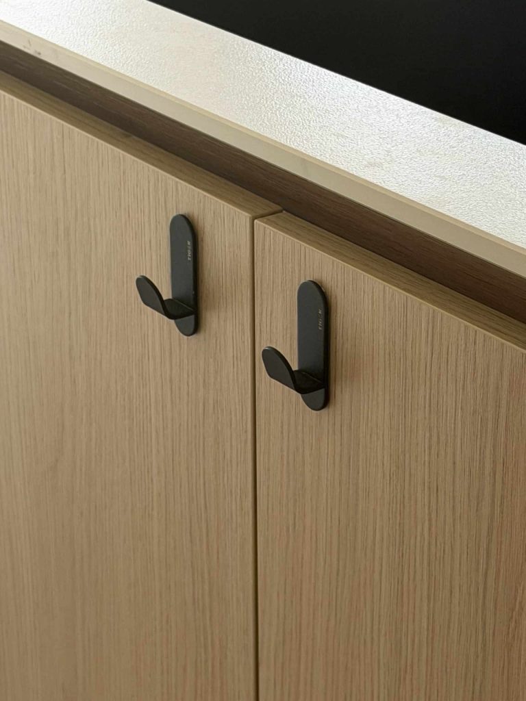 Interieur detail van houten kastdeuren met zwarte kledinghaken