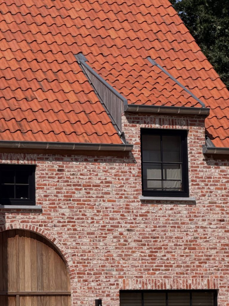Close-up van rood pannendak met dakkapel en bakstenen gevel