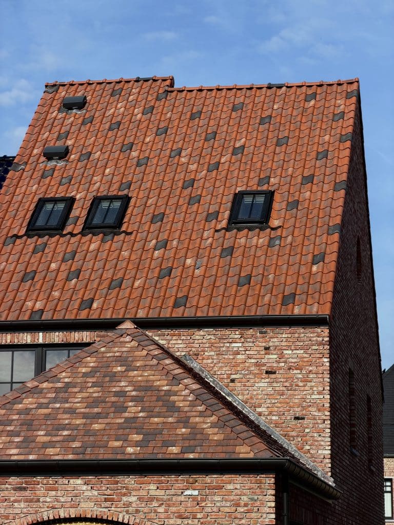 Detail van rood pannendak met kleine dakvensters en schoorsteen