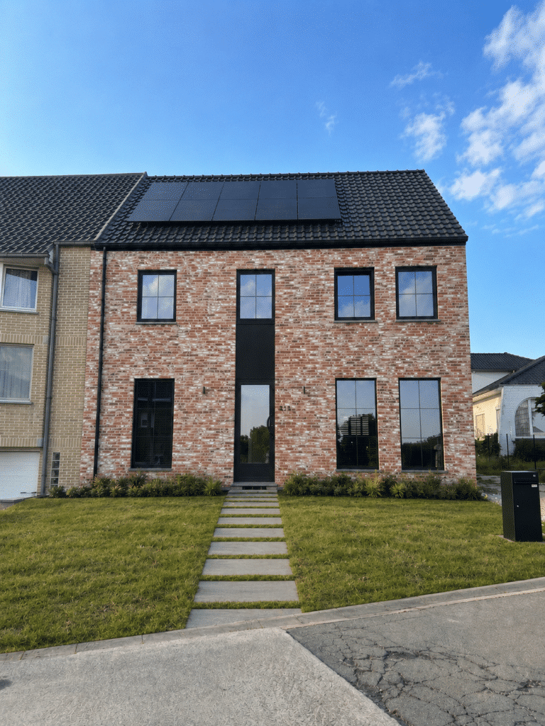 Bakstenen rijhuis met zwart pannendak, zonnepanelen en grote raampartijen