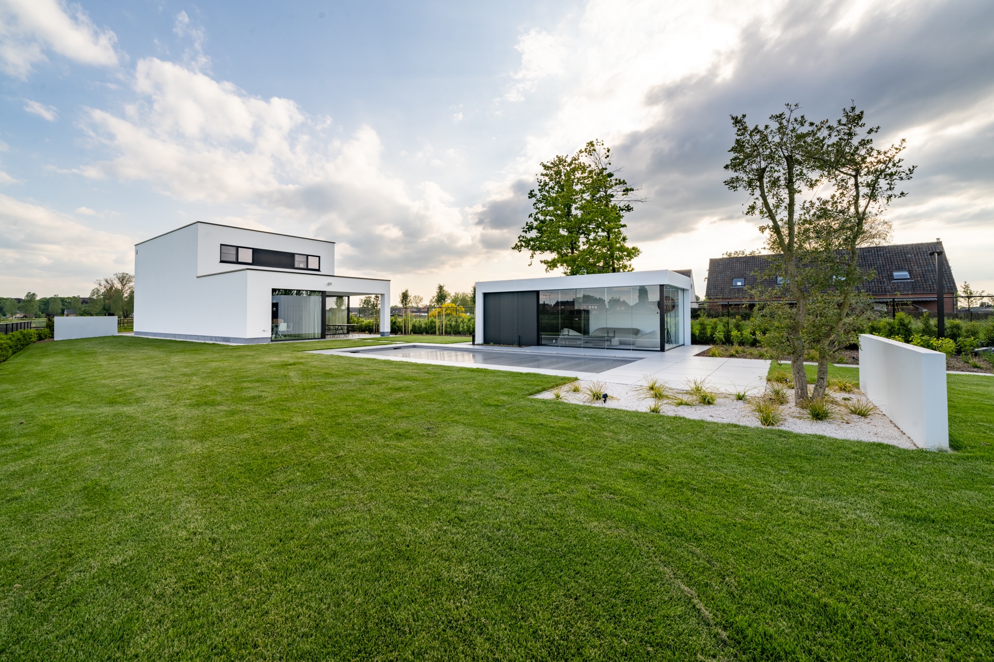 Open bebouwing met moderne witte gevel, ruime tuin, zwembad en poolhouse