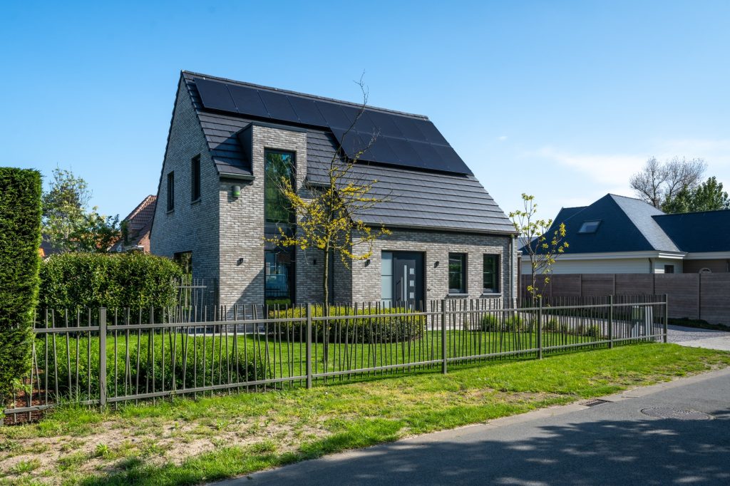 Vrijstaande woning met zonnepanelen, grijze gevelsteen en aangelegde voortuin