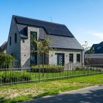 Vrijstaande woning met zonnepanelen, grijze gevelsteen en aangelegde voortuin