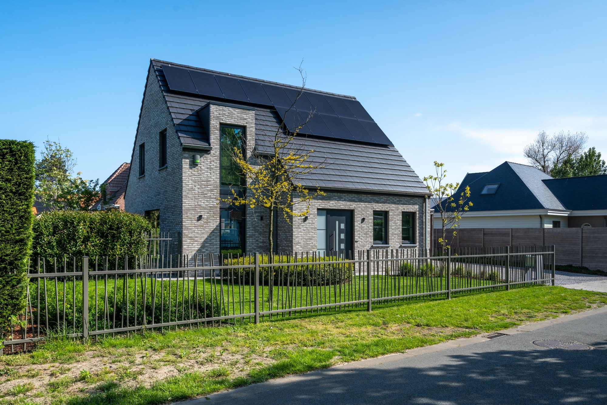 Vrijstaande woning met zonnepanelen, grijze gevelsteen en aangelegde voortuin